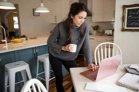 Woman planning home improvements on laptop in kitchen