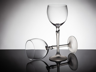 Two empty glasses on a white-lit table, one - lies