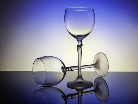 Two Empty Glasses On A Blue-lit Table, One - Lies