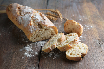 Baguette demi-tranchée ou pain français cuit avec des oignons sur du bois rustique foncé