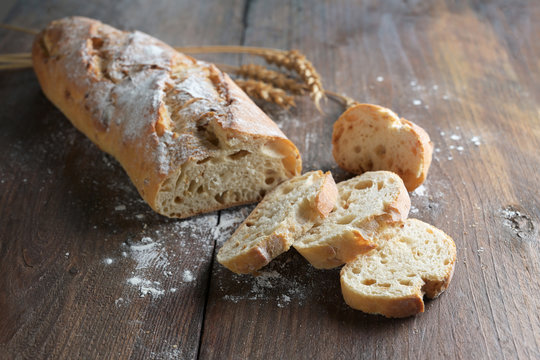 Half sliced baguette or French bread baked with onions on dark rustic wood