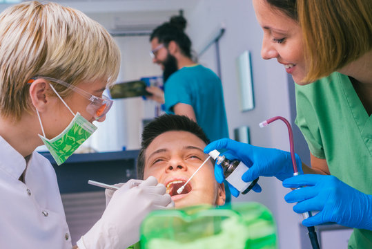 Closeup picture of a female dentist examining teenage boy's teeth in the dental office.