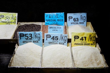 Array of different sorts of dry rice openly displayed in wooden boxes at a public market in Iloilo,...