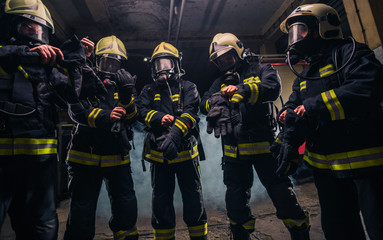 Team of firefighters in the fire department wearing gas masks and uniform