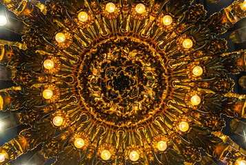Abstract image looking up at a lite chandelier with golden accents.