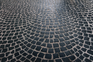 Fototapeta premium The paving stones laid laid out in a semicircle. The texture of the old dark stone. Road surface. Vintage, grunge.