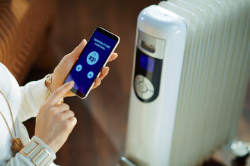 Closeup on woman using smartphone app for temperature control