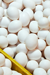 Close-up of a heap unsorted white eggs in a tray for sale in wet market in Iloilo, Philippines, Asia. Eggs are naturally dirty and slightly damaged