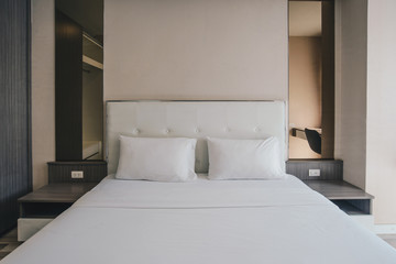 View of comfortable Queen size bed in hotel bedroom decoration in cozy style. Conceptual of a room in a home where people sleep.