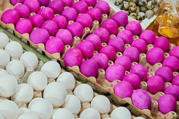 White eggs next to red colored steamed preserved salty eggs, and quail eggs for sale at a wet market in Iloilo, Philippines, Asia. Diagonal display.