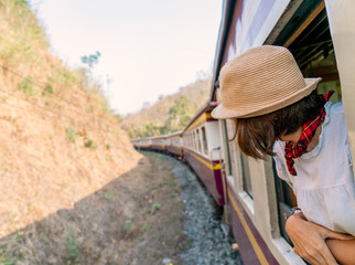 Woman looks out from window traveling by train in Thailand