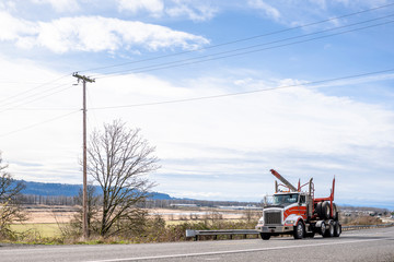 Big rig powerful semi truck transporting empty semi trailer for specialized transportation of logs running on the road