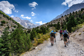 Fototapeta premium Turkey, Chamard - August 3, 2019: Tourists walk along the road through the mountain landscape in the Turkish national Park aladag in summer day, view from the back