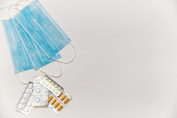 Medical masks and tablets on a white background top view. Recommendation of virus protection and prevention and treatment of colds.