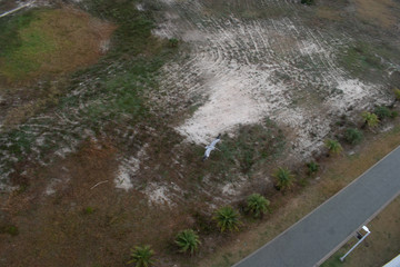 looking down on flying pelican over sandy natural beach