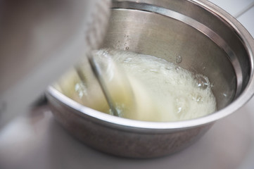 Beating egg white with electric whisk, elevated view.