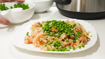 Rice with meat and vegetables (Rice Pilaf) cooked in multicooker, close up on on a plate with white background