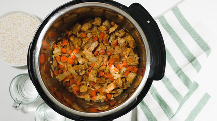 Cooking rice with meat and vegetables  in pressure multi cooker step by step, top view. Saute chopped marinated meat and vegetables.