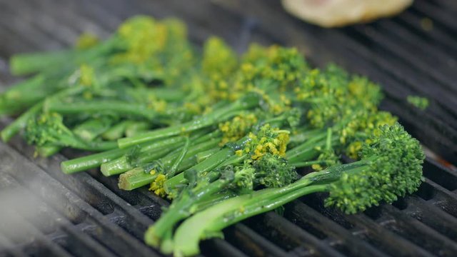 Fresh broccolini on a hot grill in a restaurant kitchen, close up.