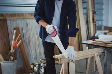 Asian man Carpenter working with technical drawing or blueprint construction paper lying on a workshop with carpentry tools and wood at home