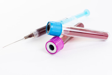 Syringe and blood vacuum test tubes on white background.