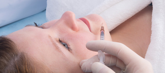 Naklejka premium cosmetology, hands in sterile gloves make an injection of beauty to a woman, in the chin