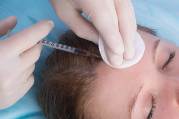 cosmetology, hands in sterile gloves, make a beauty injection to a woman with closed eyes, in the...