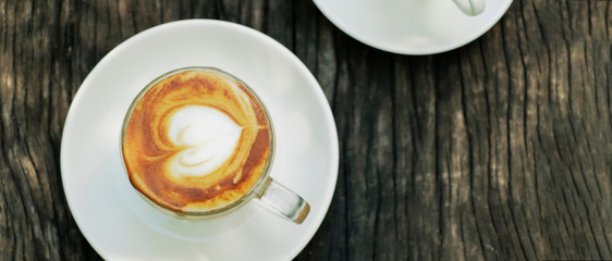 Coffee with foam art in heart shape on rustic wooden table, banner design