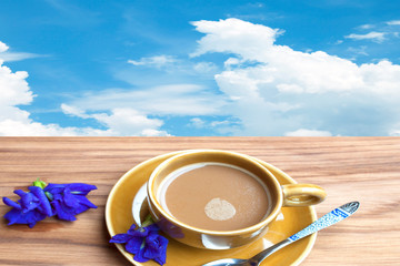 Coffee mug on wooden plate with sky