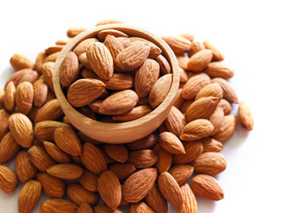 Top view of almond seeds in wooden bowl isolated on white background.