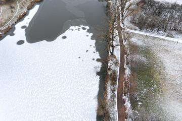 aerial view of the snowy river and footpath on riverbank in winter city park