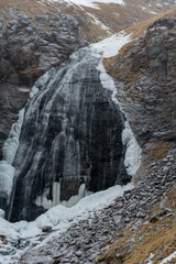 Fototapeta na wymiar Vertical landscape view of frozen Girl's Braids waterfall on Elbrus mountain, Northern Caucasus. Snow flakes falling in the foreground.