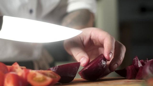 chef in kitchen cuts beetroot for salad. vegetables on cutting Board. cook in kitchen prepares ingredients for delicious meal. cooking salad with vegetables. dietary food. healthy product Vegetarian