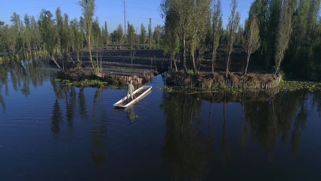 Aerial shot of old man rowing a boat in Xochimilco
