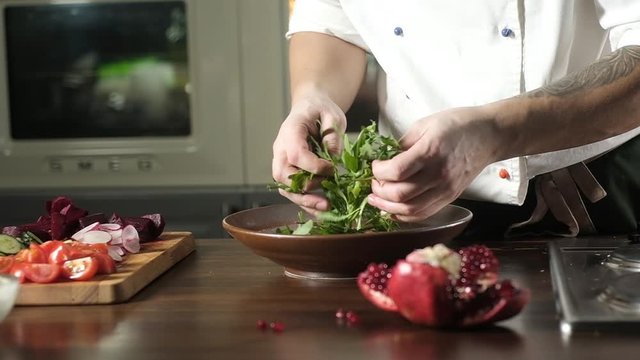 preparation of salad. Arugula with vegetables. Preparing ingredients in the kitchen. The chef is stirring a fresh green salad in a plate. Cooking gourmet meals in the restaurant's kitchen.