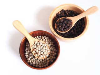 White pepper and black pepercorn in wooden spoon isolated on white background.
