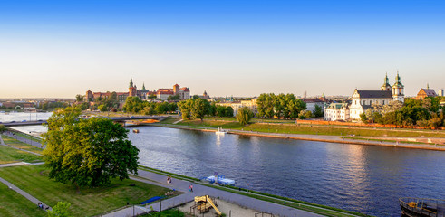 Krakow, Poland. Aerial panorama with Wawel cathedral and castle, Skalka church, Paulinite monastery, Vistula river, bridge, playground, parks and promenades along the riverside. Summer, sunset light