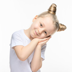 A little blonde girl in a white t-shirt folded her hands under her head. The concept of wanting to sleep or tenderness.