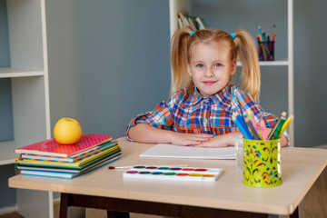 cute preschool girl paints at home at the table.