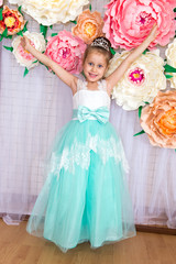 Portrait of happy girl dressed as bride in turquoise dress with diamond diadem
