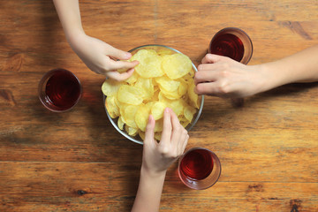 Big family eating potato chips from bowl, top view