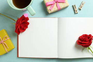 Empty note paper with red rose flower, black coffee, gift boxes on mint green background. Flat lay, top view, copy space