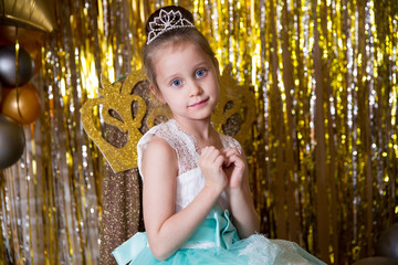 Cute girl folded her arms in the shape of a heart. Turquoise dress and diamond diadem