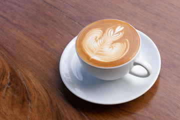 Coffee cup with latte art foam on wood table in coffee shop with copy space.Coffee is one of the...
