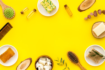 Hair care concept. Coconut oil, brush on yellow background top-down frame copy space