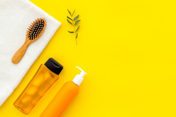 Bath set. Shampoo, towel, brush on yellow background top-down frame copy space