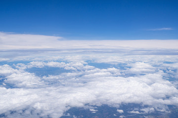Fototapeta na wymiar Beautiful view from airplane window above the clouds. Bright blue sky and white clouds. Skyline background with copy space.