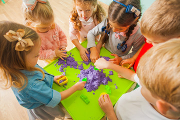 Top view of little children making forms with kinetic sand