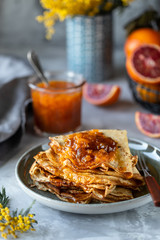Pancakes with jam or marmalade made from red orange. Tasty breakfast. Crepe suzette pancakes with orange sauce.