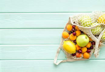 Eco-friendly package. Eco bag with fruits on green wooden background top-down copy space